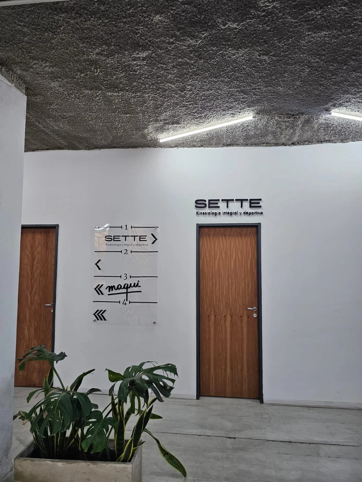 Entrada de Sette con señalética de acrílico y cartel de polifan