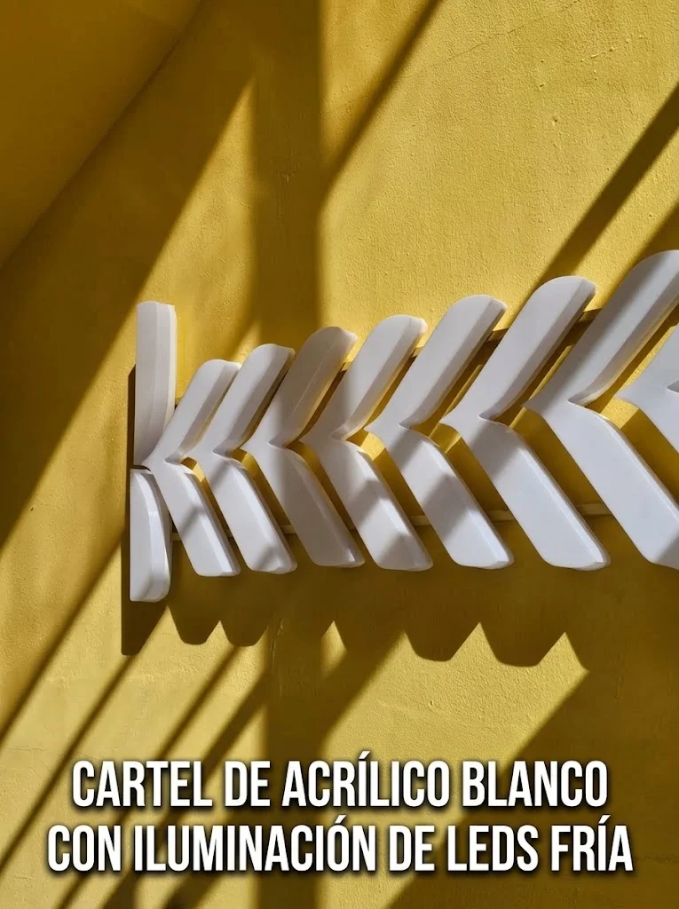 Cartel de acrílico blanco con iluminación LED fría sobre pared amarilla