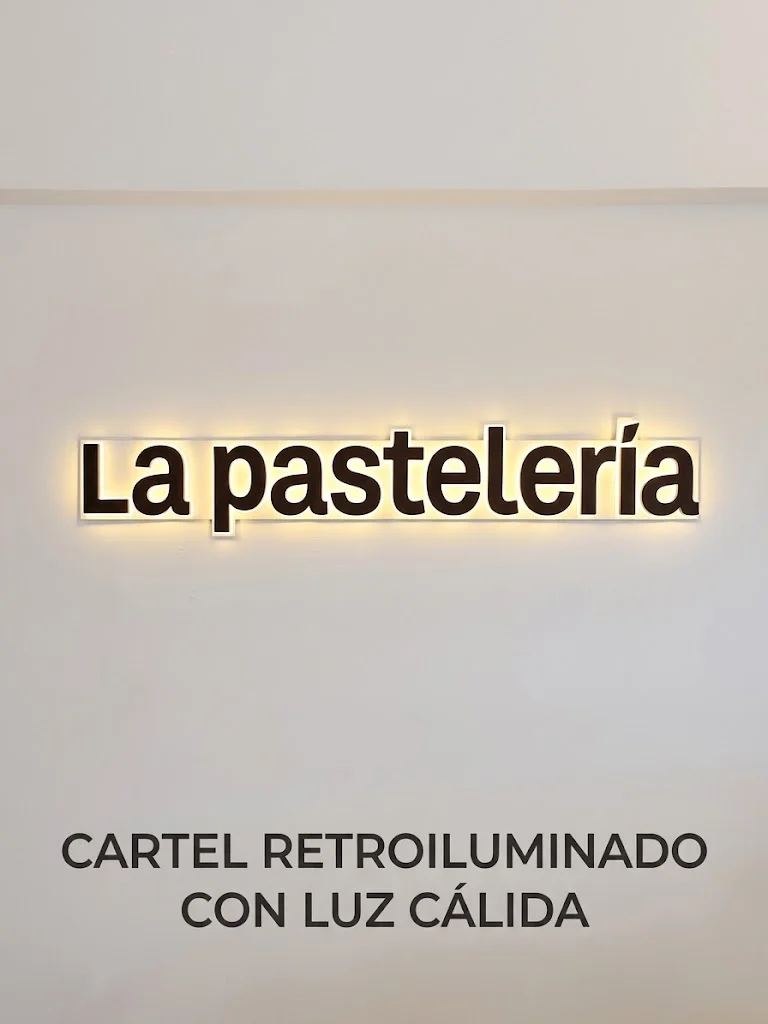 Letras de La Pastelería con halo de luz cálida sobre la pared