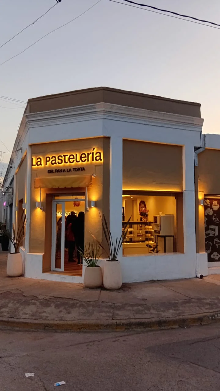 Fachada de La Pastelería con el cartel retroiluminado al atardecer